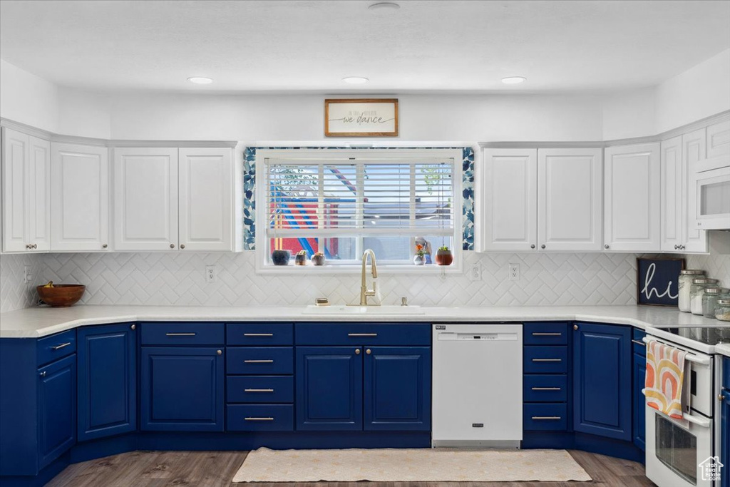 Kitchen with white appliances, white cabinets, dark wood finished floors, and a sink