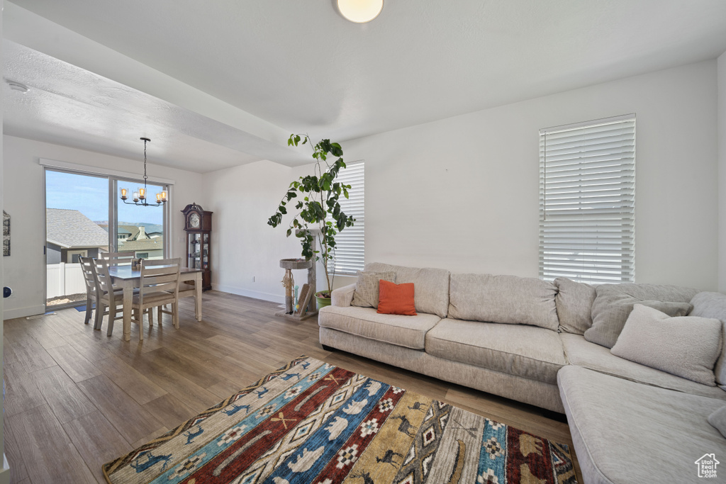 Living area with baseboards, an inviting chandelier, and wood finished floors