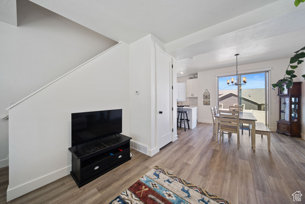 Living room with baseboards, a notable chandelier, visible vents, and wood finished floors