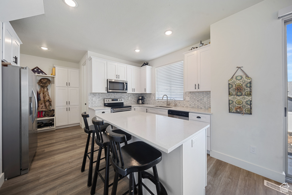 Kitchen with tasteful backsplash, dark wood finished floors, a sink, light countertops, and stainless steel appliances