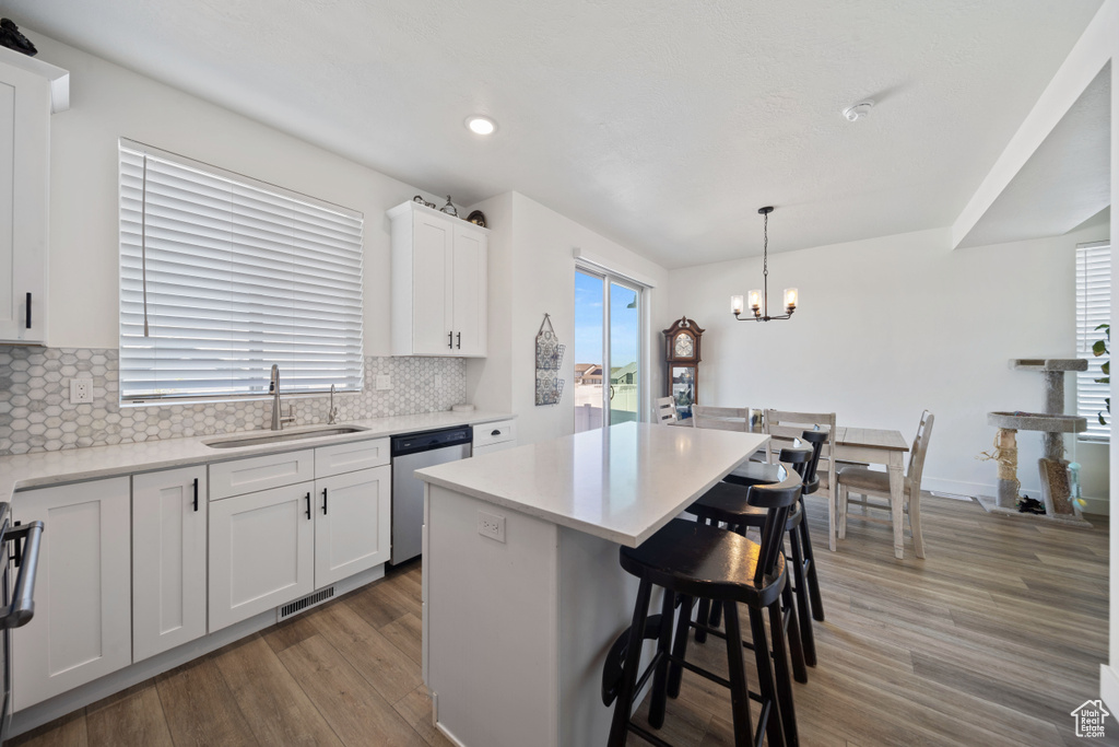 Kitchen with a notable chandelier, a sink, a kitchen bar, stainless steel dishwasher, and visible vents