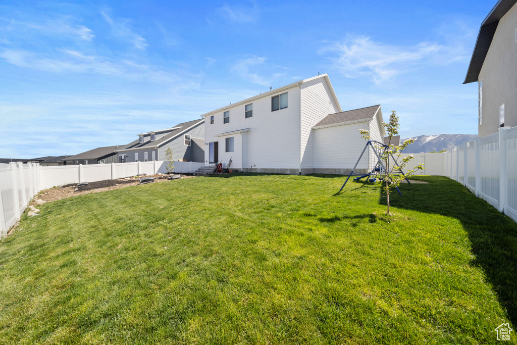 Back of property with a playground, a yard, and a fenced backyard