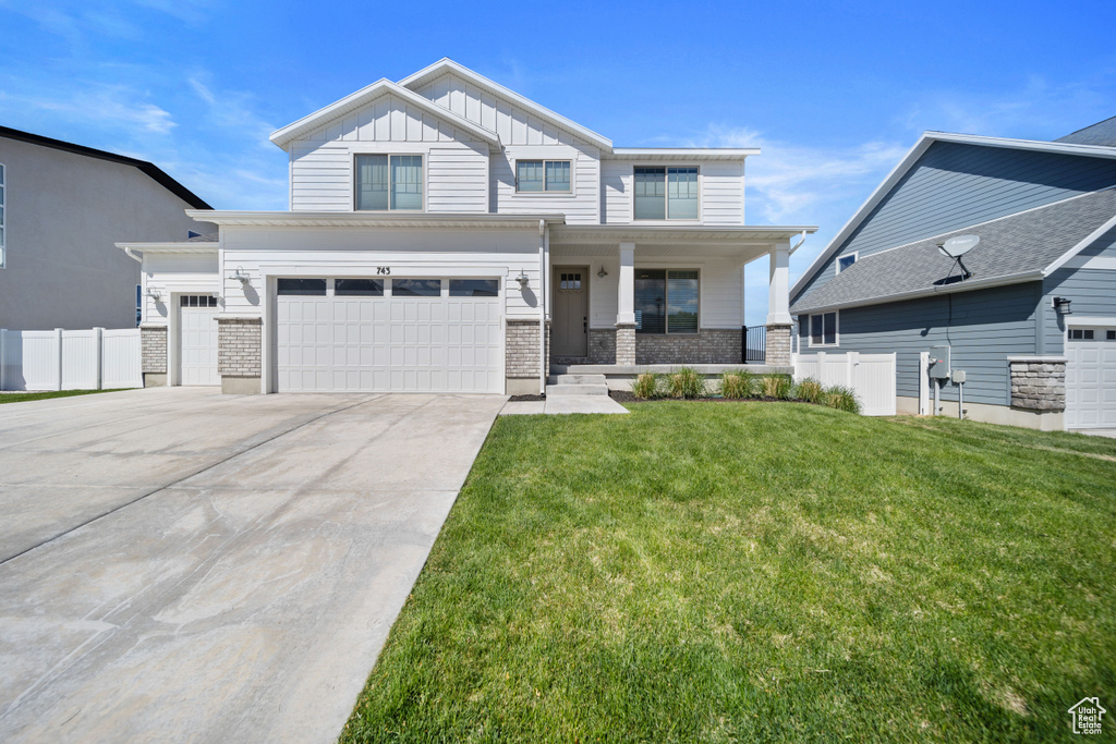 View of front of home featuring board and batten siding, fence, covered porch, and a front yard