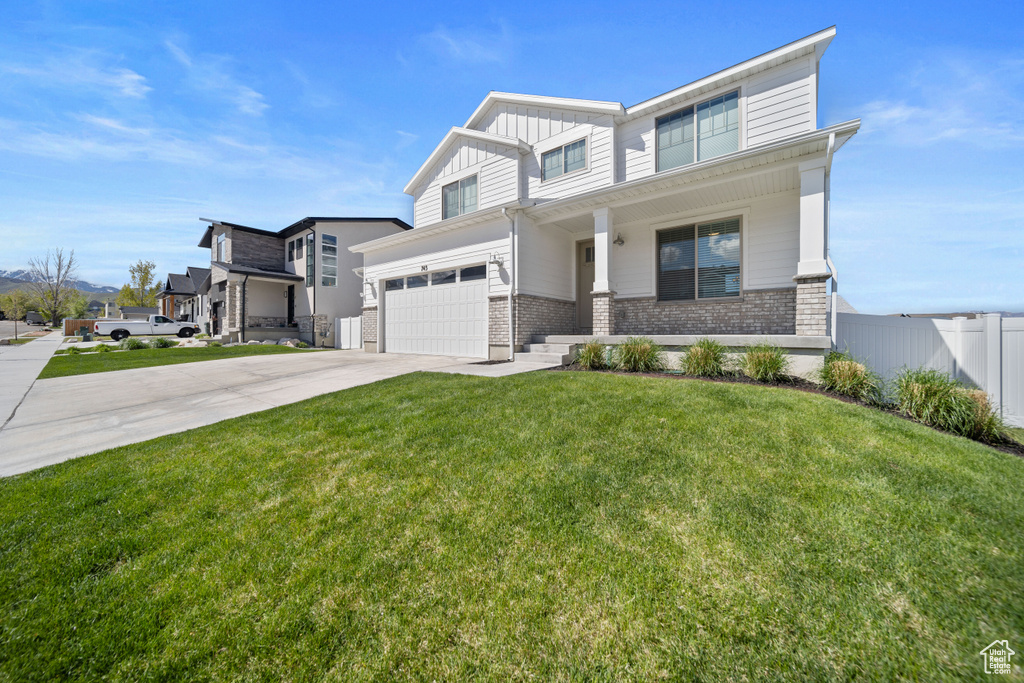 View of front of home with a porch, driveway, brick siding, fence, and an attached garage