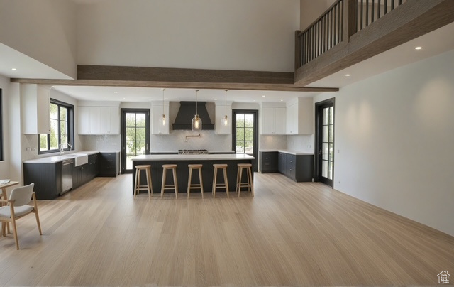 Kitchen featuring white cabinets, light wood-style floors, dishwasher, a kitchen breakfast bar, and premium range hood