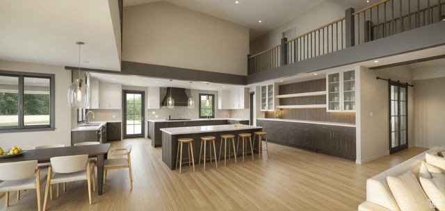 Kitchen featuring wall chimney range hood, a center island, a sink, a high ceiling, and a breakfast bar