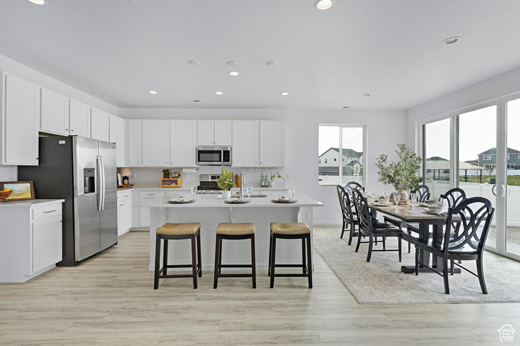 Kitchen featuring light countertops, recessed lighting, appliances with stainless steel finishes, and a kitchen breakfast bar