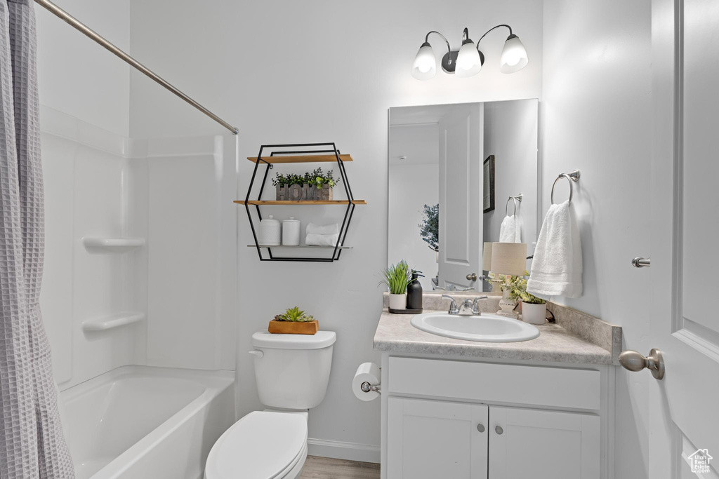 Full bathroom with vanity, shower / bath combo, and toilet