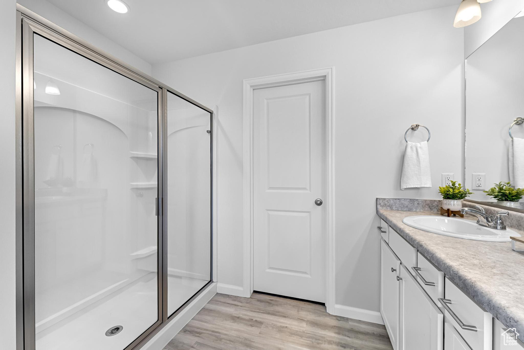 Bathroom featuring vanity, baseboards, wood finished floors, and a shower stall