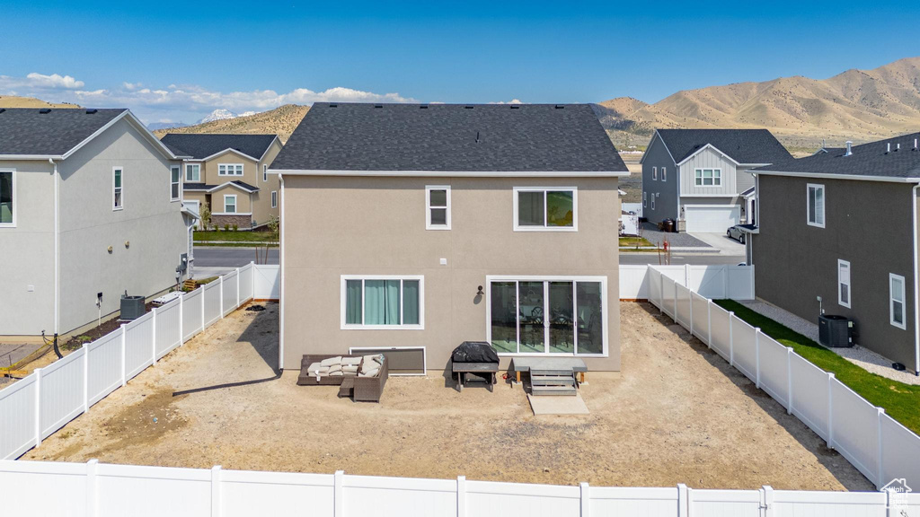 Rear view of house with a residential view, a mountain view, an outdoor hangout area, and central AC