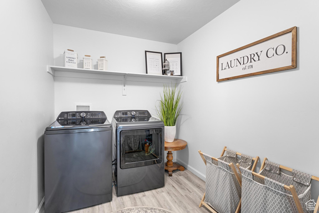 Laundry area with laundry area, baseboards, wood finished floors, and separate washer and dryer