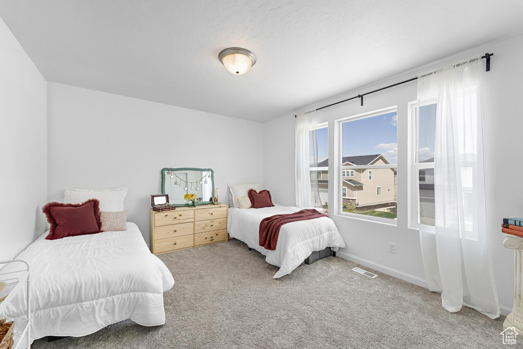 Carpeted bedroom featuring baseboards and visible vents