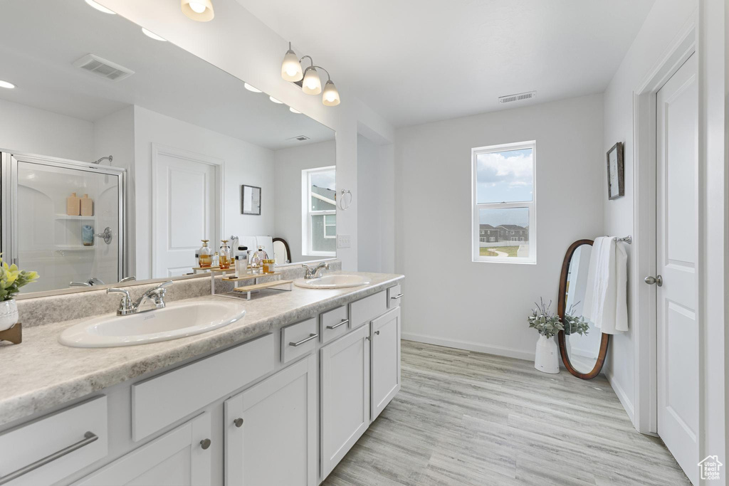 Bathroom with a sink, a stall shower, double vanity, and visible vents