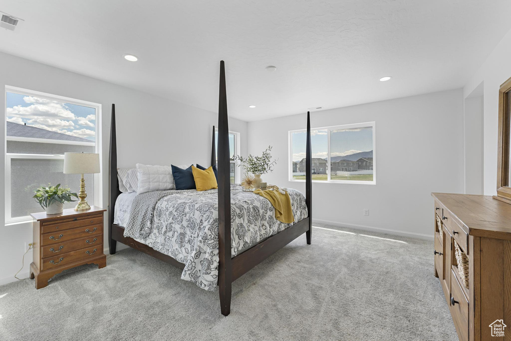 Bedroom with recessed lighting, light colored carpet, and multiple windows