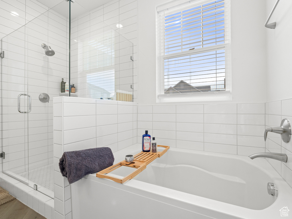 Bathroom with a bath, a shower stall, and wood finished floors