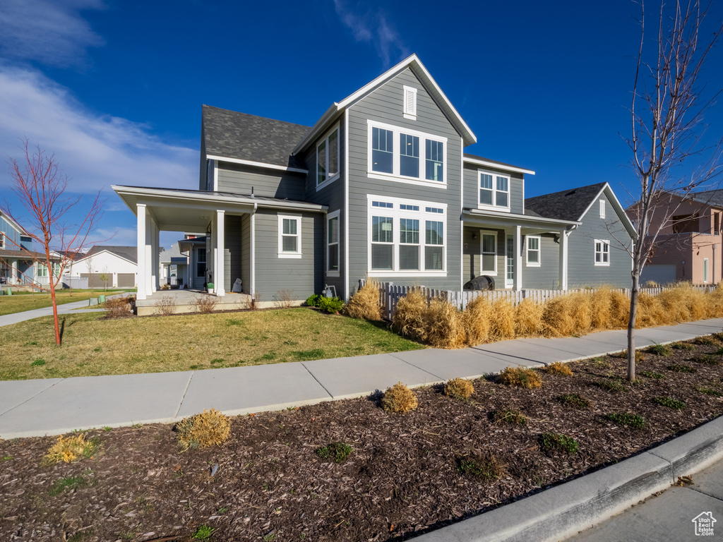 Traditional-style house featuring covered porch and a front yard