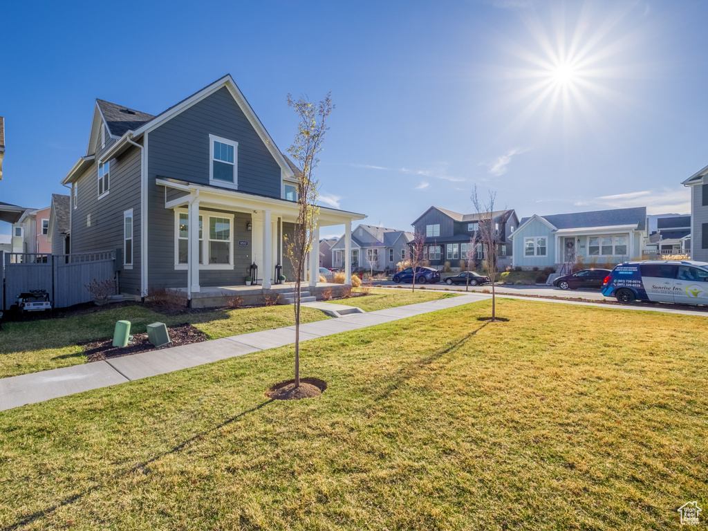 View of front of house with a porch, a front yard, and a residential view