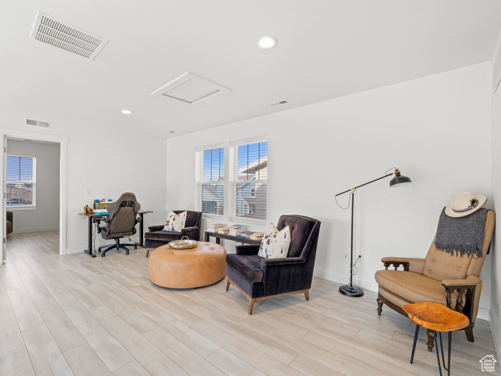 Living area featuring visible vents, light wood-type flooring, and attic access