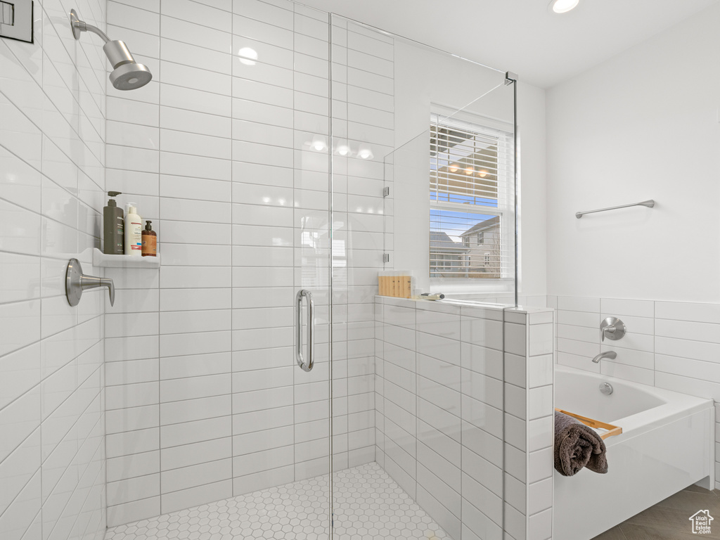 Bathroom featuring tile walls, a bath, and a stall shower
