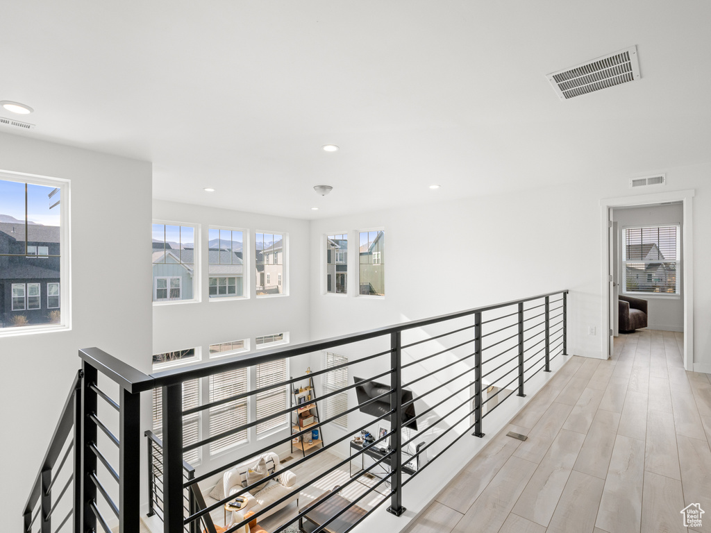 Hallway with an upstairs landing, visible vents, and a healthy amount of sunlight