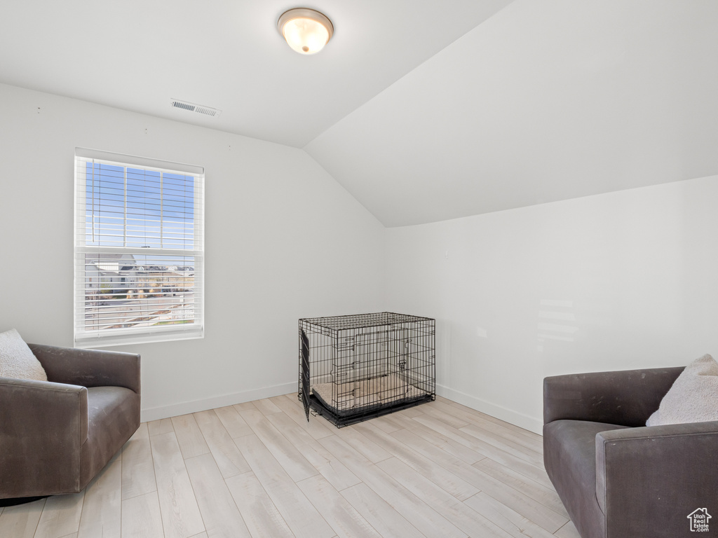Living area with wood finished floors, baseboards, lofted ceiling, and visible vents