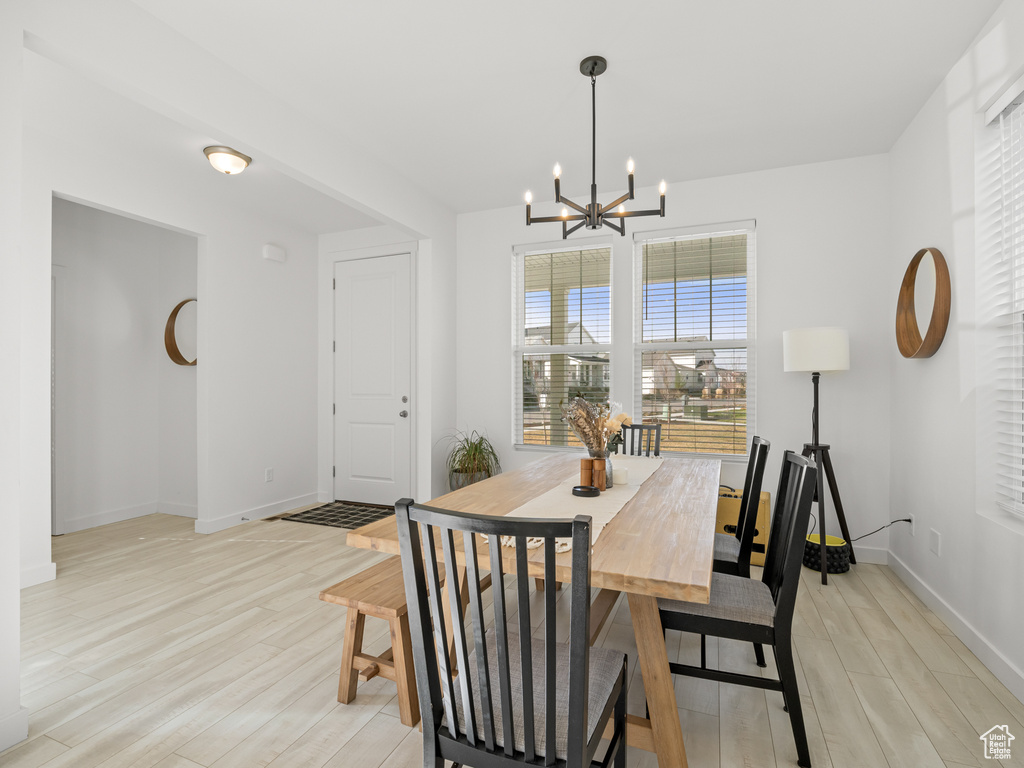 Dining room featuring light wood finished floors, a notable chandelier, and baseboards