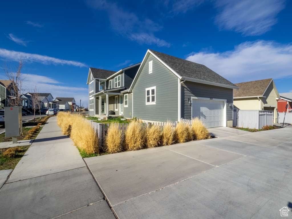 View of property exterior with a garage, a residential view, driveway, and fence