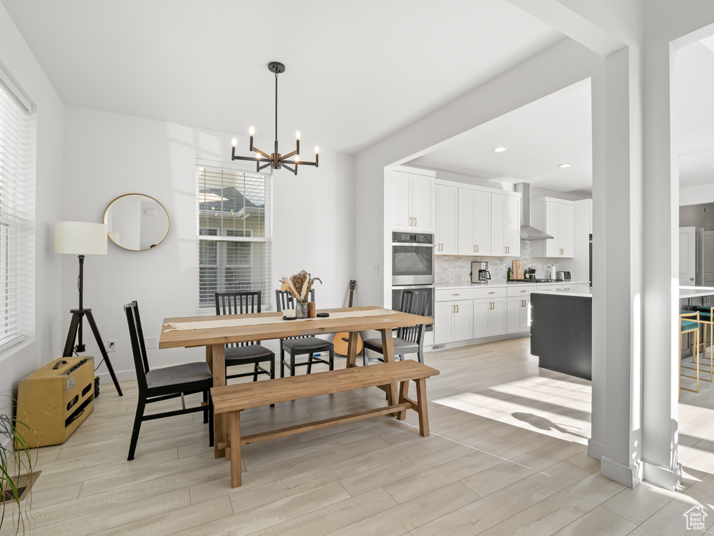 Dining area with light wood-style floors, a notable chandelier, and recessed lighting