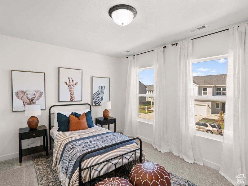 Bedroom featuring light colored carpet, visible vents, and multiple windows