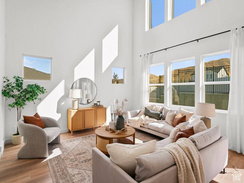 Living room featuring baseboards, a high ceiling, and light wood finished floors