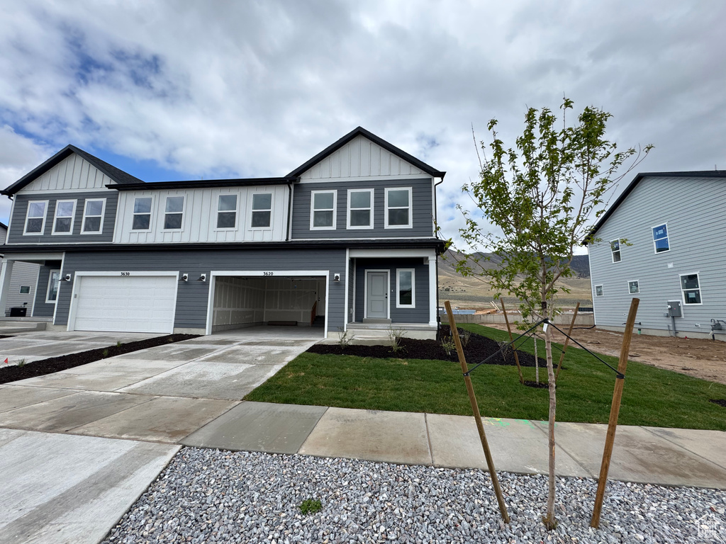 View of front of property with fence, driveway, a garage, a front lawn, and board and batten siding