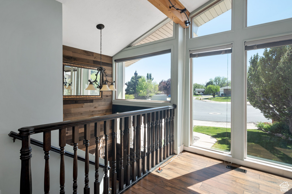 Interior space with wooden walls, visible vents, a chandelier, hardwood / wood-style floors, and vaulted ceiling
