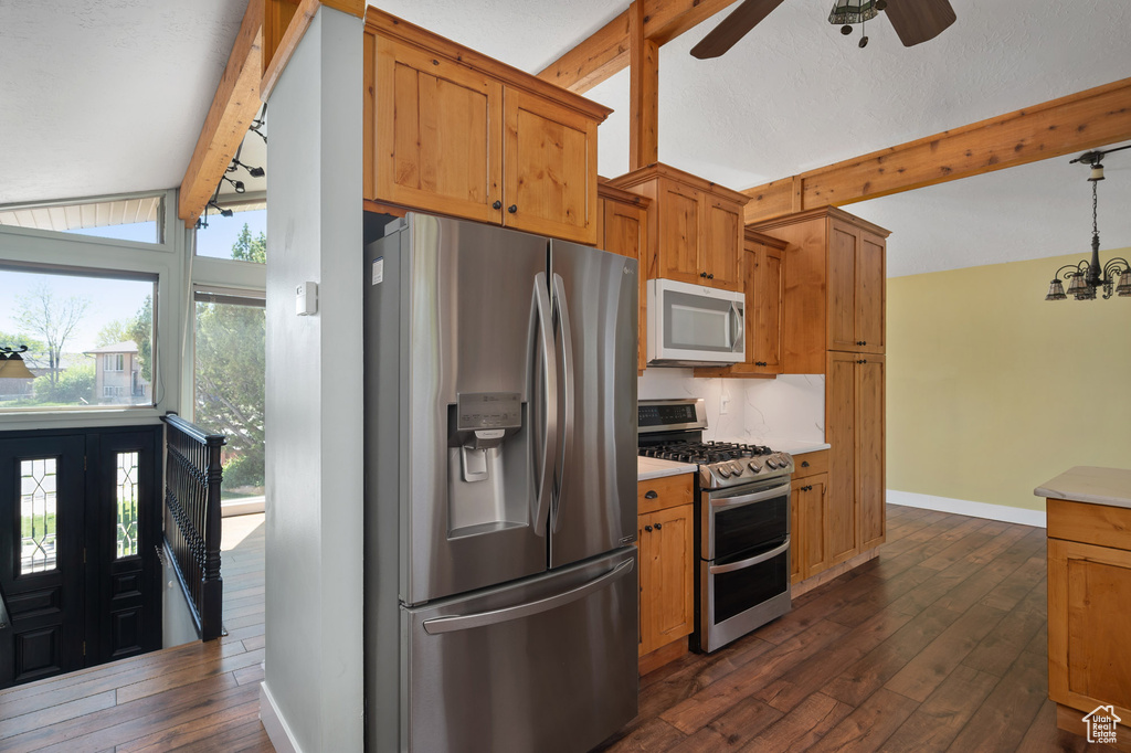 Kitchen featuring light countertops, appliances with stainless steel finishes, lofted ceiling with beams, and dark wood-type flooring