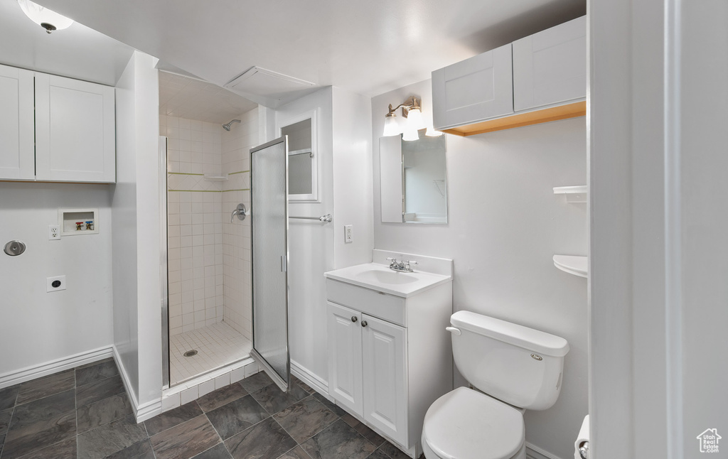 Bathroom featuring vanity, toilet, baseboards, and a stall shower