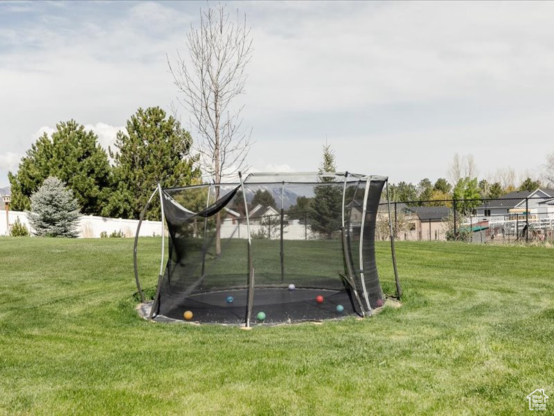 View of yard with a trampoline and fence