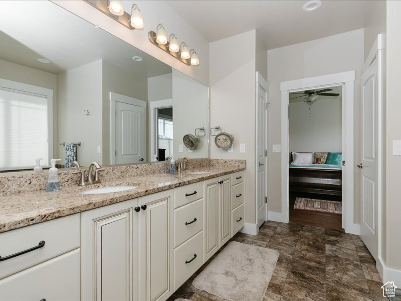 Full bath featuring double vanity, a sink, ensuite bath, and a wealth of natural light
