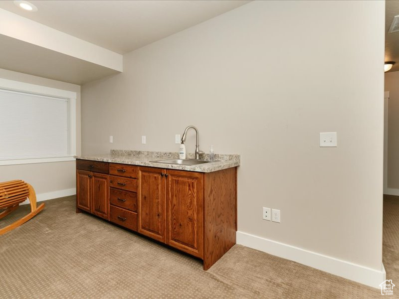 Bar featuring a sink, baseboards, recessed lighting, and light colored carpet