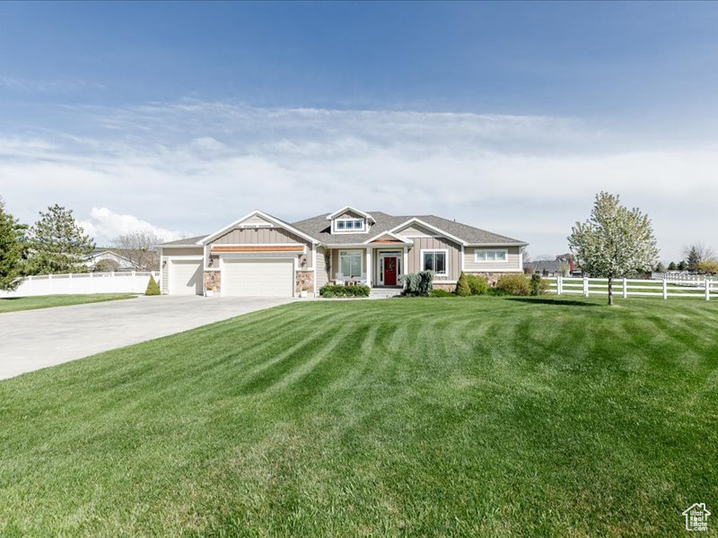 View of front of property with an attached garage, board and batten siding, fence, and a front yard