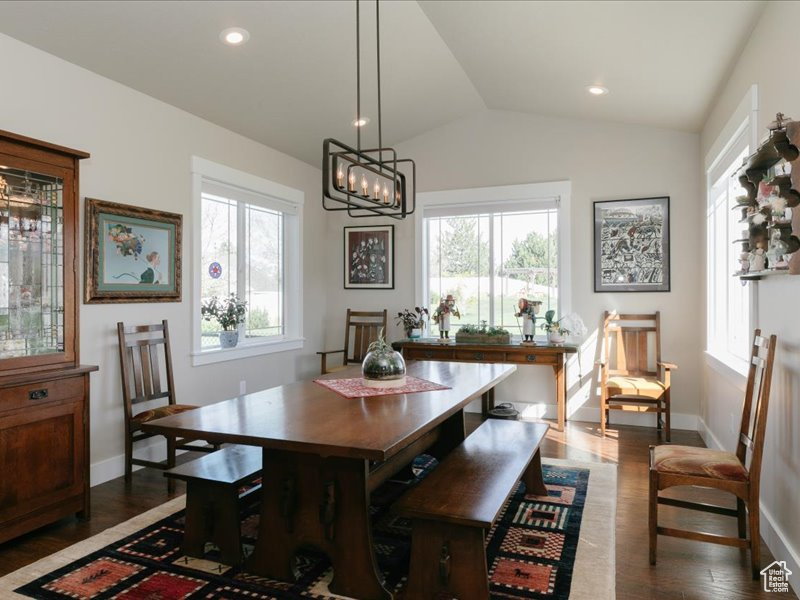 Dining space with baseboards, dark wood-style floors, vaulted ceiling, and a healthy amount of sunlight