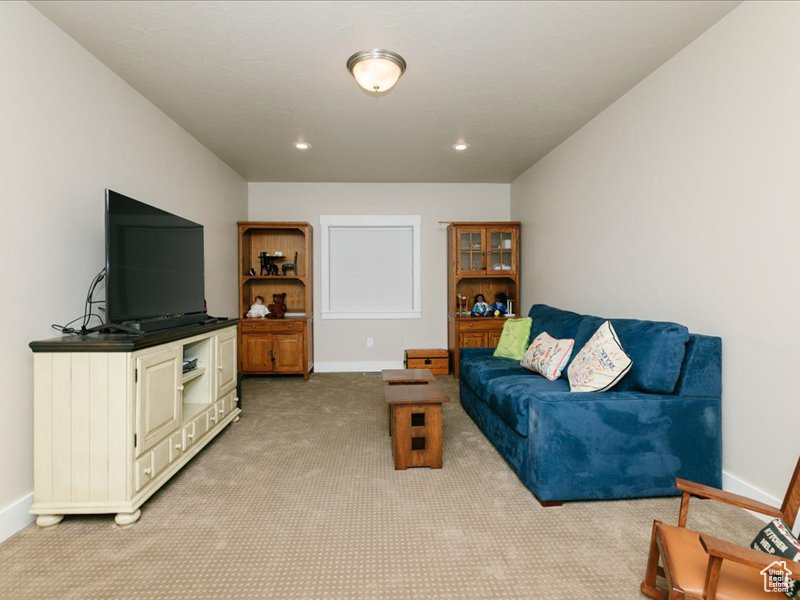 Living room featuring baseboards, recessed lighting, and light carpet