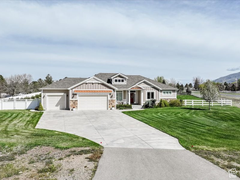 Craftsman-style home featuring fence, an attached garage, a front lawn, board and batten siding, and driveway