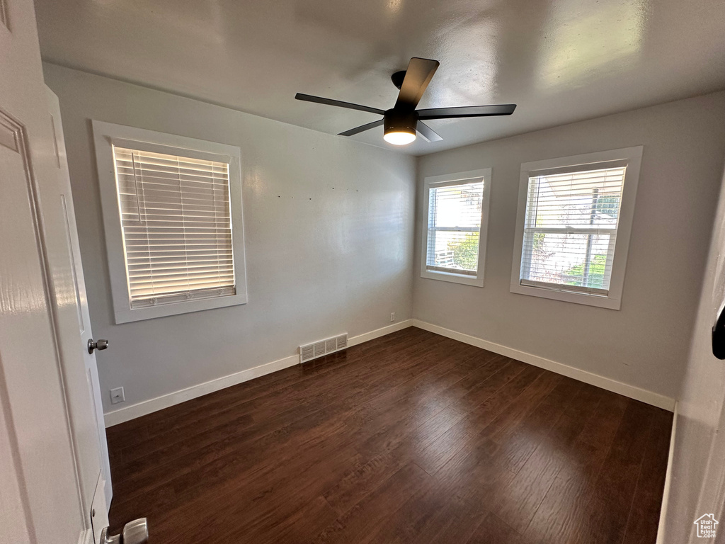 Empty room featuring dark wood-style flooring, baseboards, and visible vents