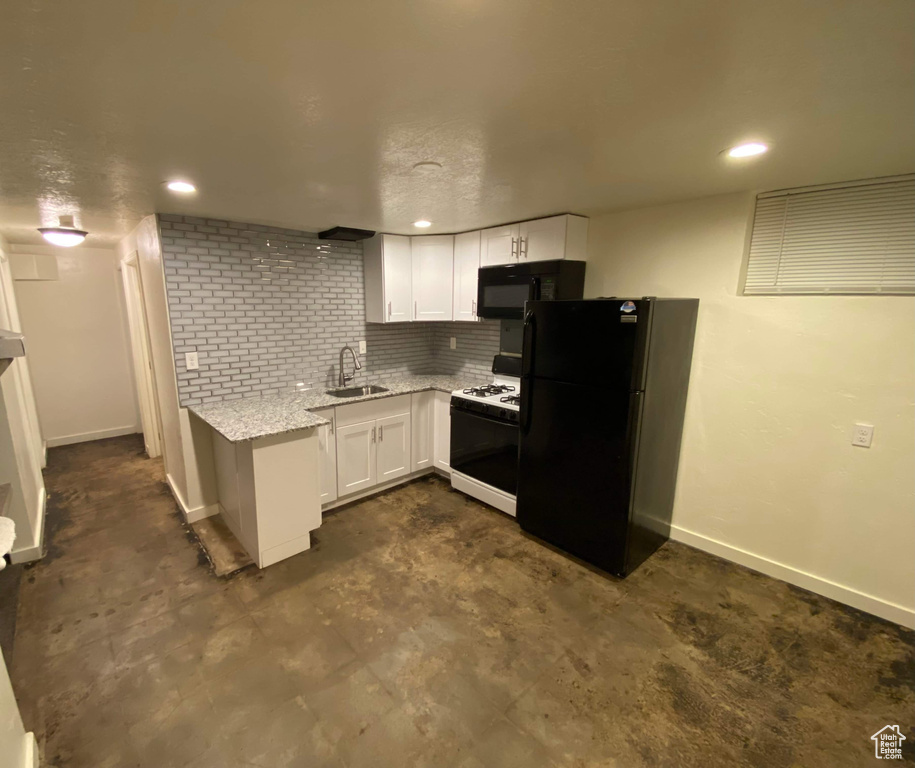 Kitchen with white cabinets, light stone counters, a sink, baseboards, and black appliances