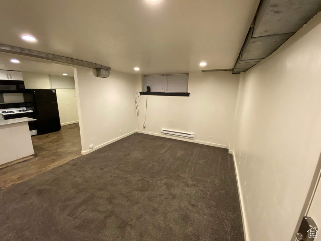 Finished below grade area featuring freestanding refrigerator, recessed lighting, baseboards, and a baseboard radiator
