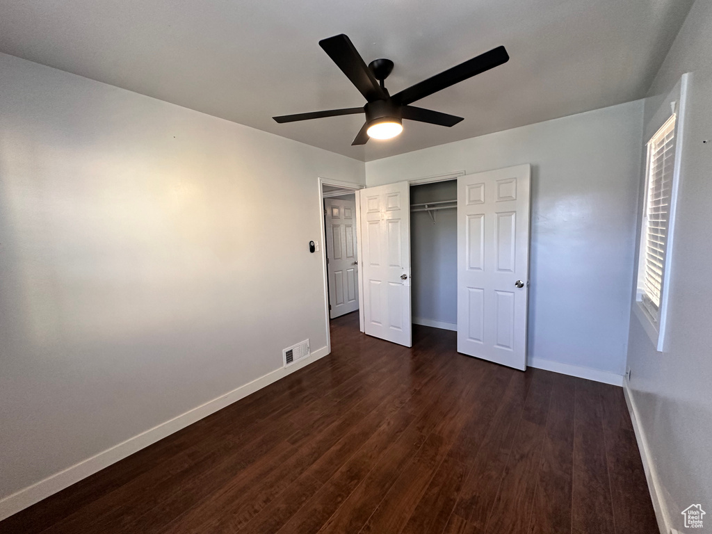 Unfurnished bedroom with baseboards, dark wood-style flooring, and a closet