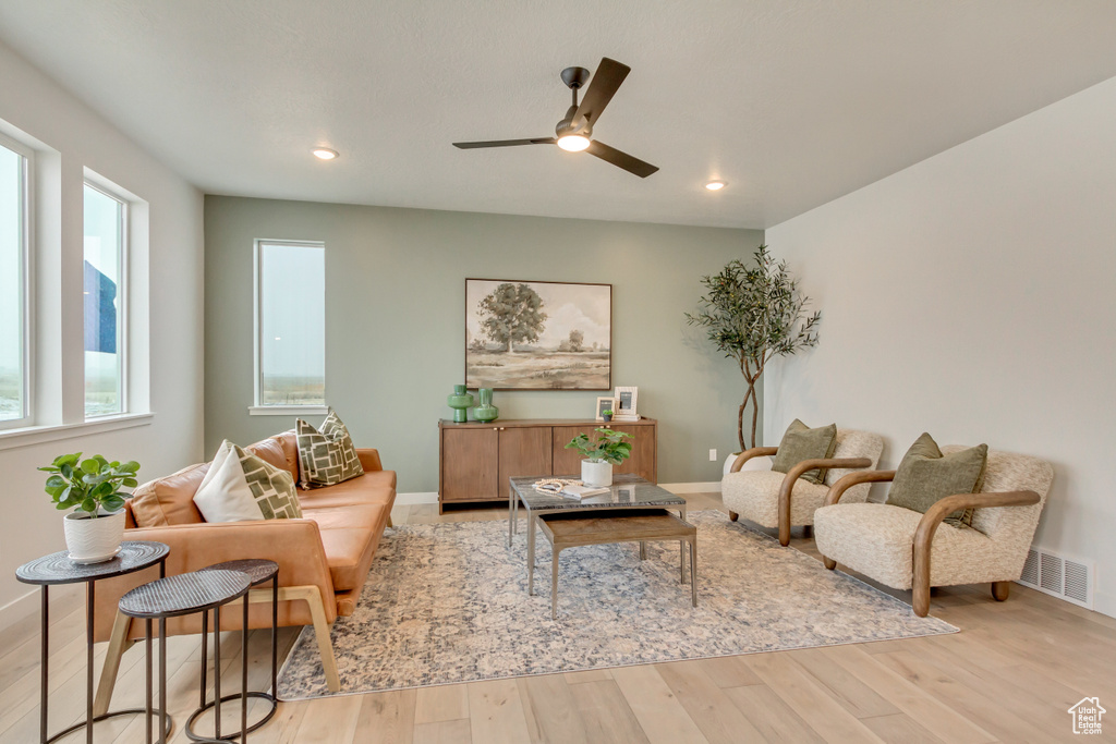 Living room with a ceiling fan, baseboards, light wood-style floors, and visible vents