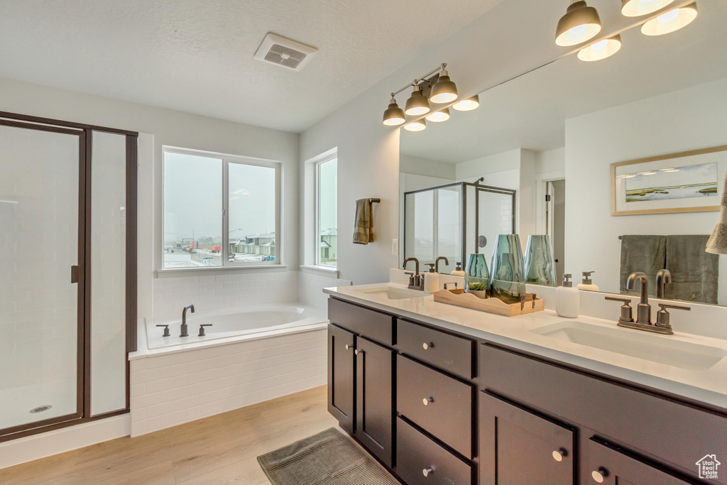 Bathroom featuring double vanity, a sink, a garden tub, and a stall shower
