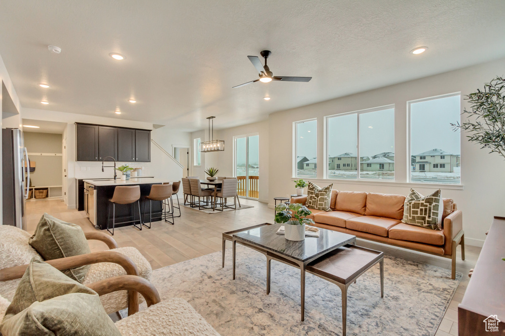 Living room with baseboards, light wood-type flooring, ceiling fan, and recessed lighting