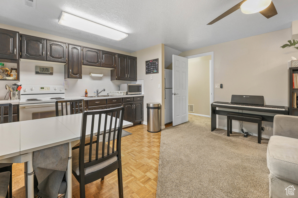 Kitchen with ceiling fan, visible vents, white electric range, light countertops, and a sink