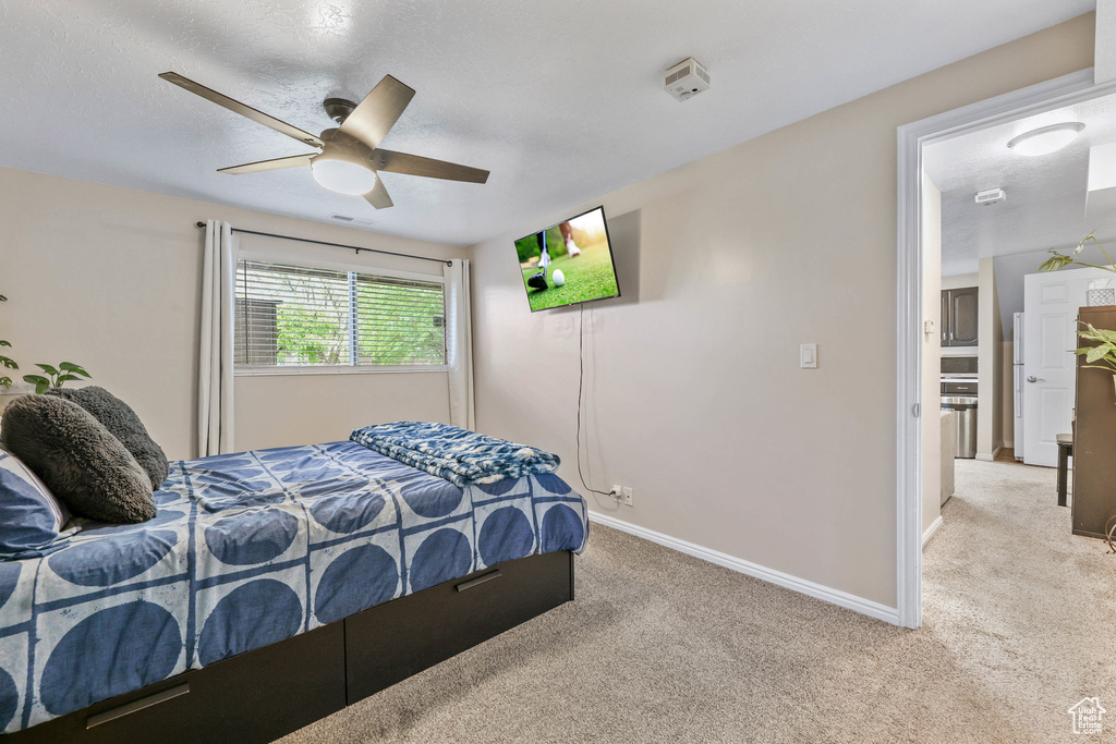 Bedroom with baseboards, light colored carpet, and ceiling fan